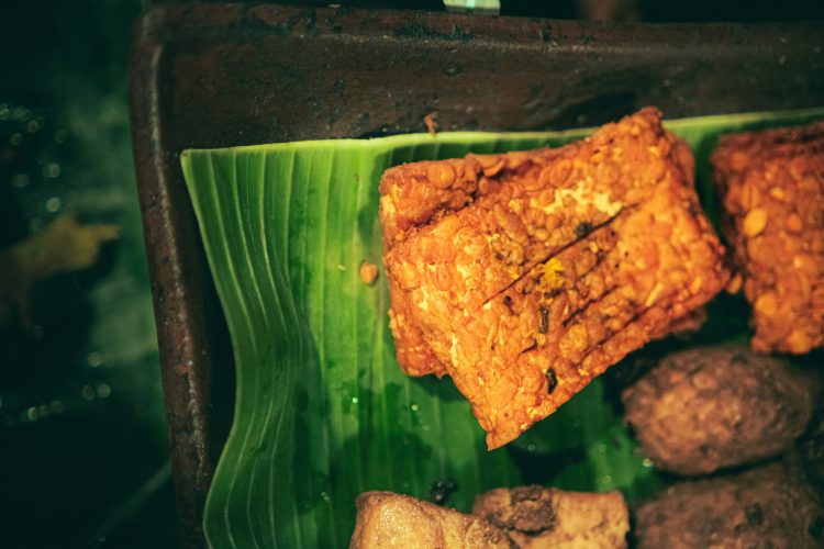 Tempe goreng crispy berwarna keemasan tersaji di piring sebagai camilan dan lauk rumahan
